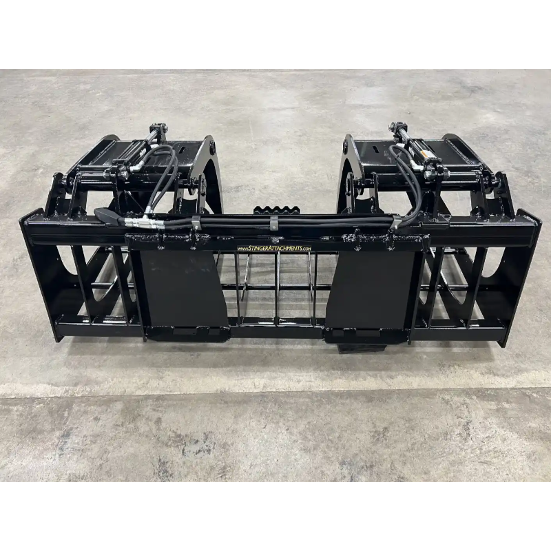 Black steel skid steer root and rock grapple attachment with hydraulics, spaced tines, and reinforced side panels on concrete floor