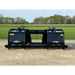 Black steel dual grapple attachment with hydraulic arms, solid side panels, and reinforced tines on gravel surface
