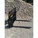 Black steel skid steer pallet fork attachment with grid backrest and two extended forks on gravel surface outdoors