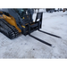 Black steel skid steer pallet fork attachment with two long tines and reinforced vertical backrest on snowy ground