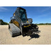 Skid steer with black tracked undercarriage and attached stump grinder with cutting wheel and hydraulic hoses on gravel lot
