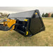 Black steel hydraulic dump bucket attachment with yellow "Stinger" logo mounted on yellow loader arm over grassy field