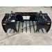 Front view of black metal manure grapple attachment with multiple curved tines and hydraulic cylinders on concrete floor