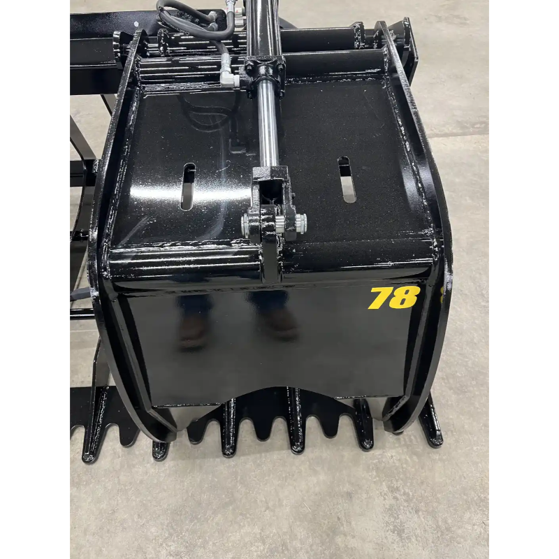 Black steel skid steer root grapple attachment with hydraulics, solid side panels, and serrated tines on concrete floor