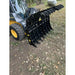 Skid steer loader with extended black steel grapple attachment featuring multiple curved tines on dirt and grass surface outdoors