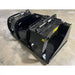 Black steel demolition grapple attachment with dual hydraulic cylinders sitting on concrete floor indoors