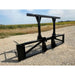 Black painted steel skid steer attachment with dual vertical supports and horizontal crossbar on gravel surface outdoors