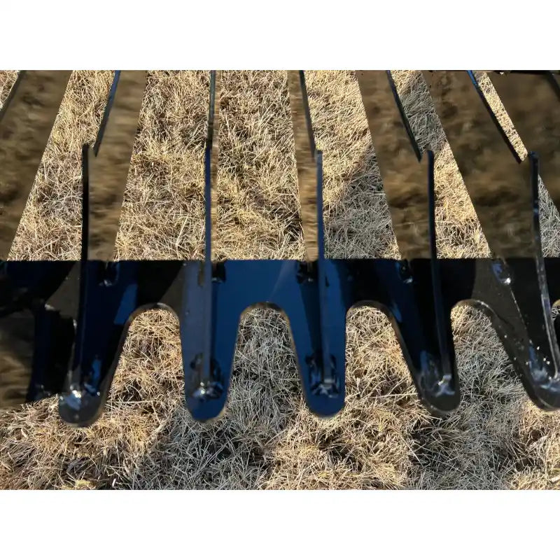 Close-up of glossy black metal grapple attachment teeth with curved, spaced tines over dry grass background