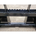 Close-up of black painted steel skid steer pallet fork attachment with reinforced tines and mounting frame on gravel surface