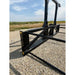 Black steel skid steer attachment with reinforced frame and multiple horizontal tines on gravel surface outdoors