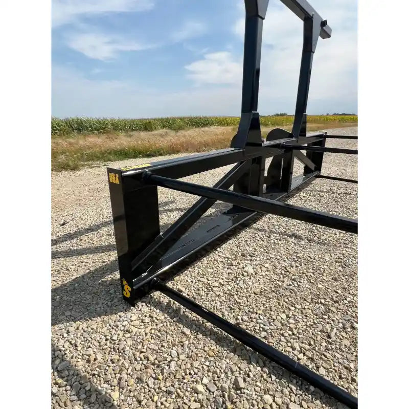 Black steel skid steer attachment with reinforced frame and multiple horizontal tines on gravel surface outdoors