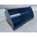Front view of a smooth black steel skid steer material bucket with welded cutting edge on gravel surface