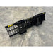 Long black metal rock bucket attachment with spaced tines and reinforced mounting brackets on concrete floor