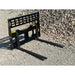 Black steel skid steer pallet fork attachment with open grid backrest and two extended fork tines on gravel surface