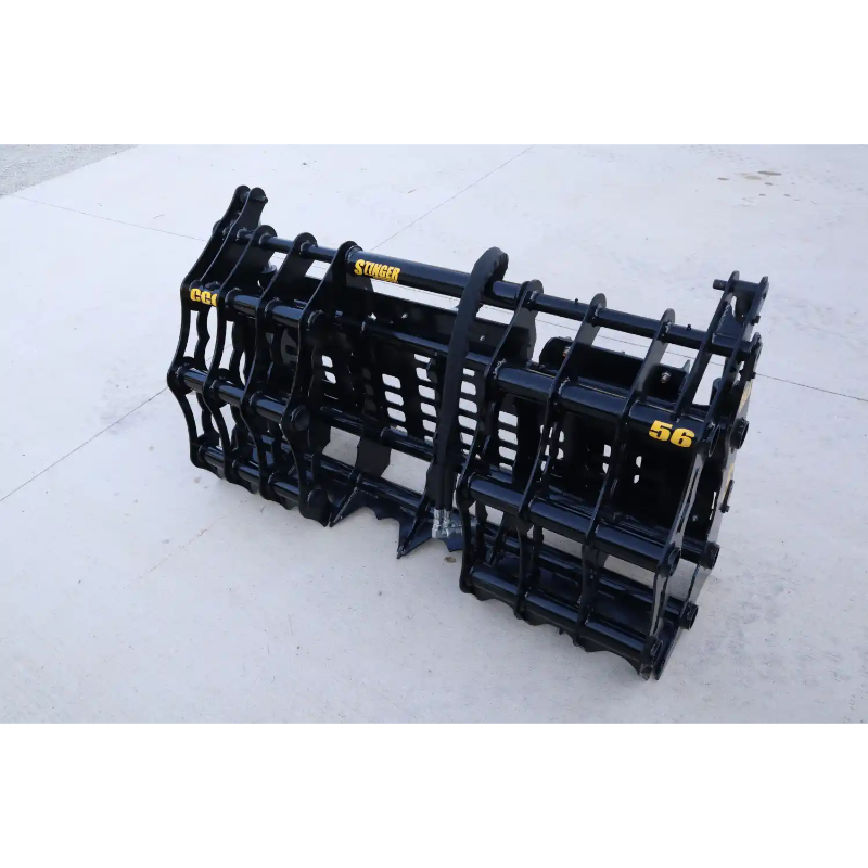 Black steel grapple attachment with hydraulic hoses and reinforced bars on concrete floor outdoors