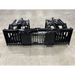 Front view of a black steel skid steer grapple attachment with wide spaced tines and dual hydraulic cylinders on concrete floor