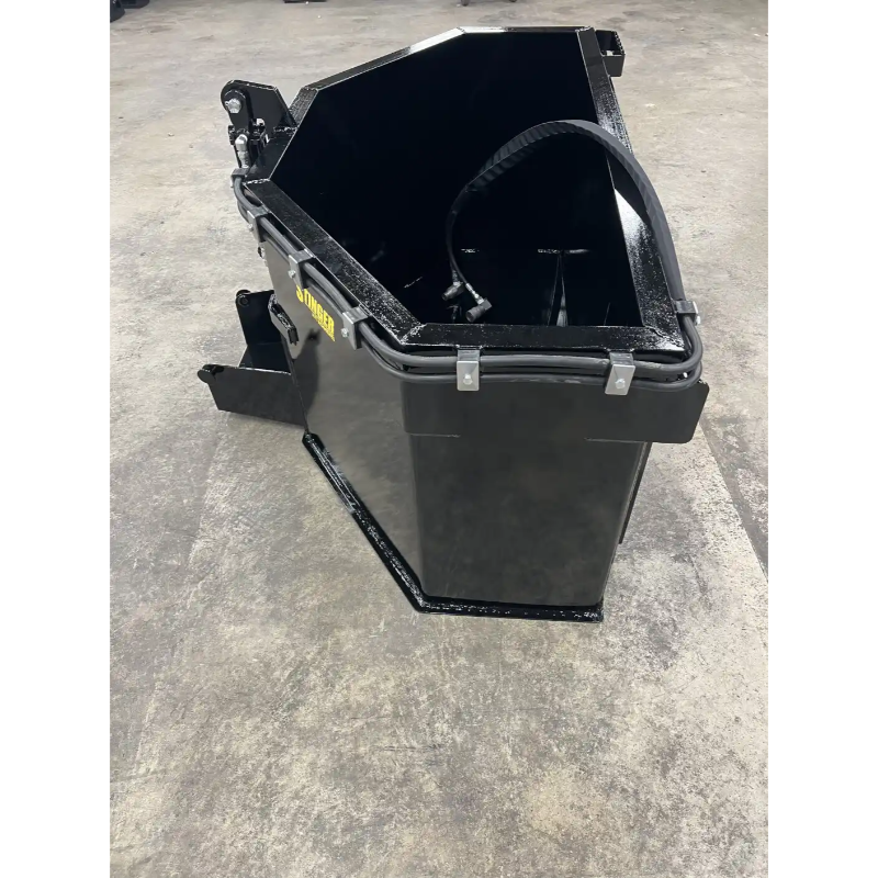Black steel skid steer concrete bucket with hydraulic hose and reinforced frame on concrete surface indoors