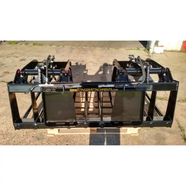 Black welded steel manure grapple attachment with dual hydraulic cylinders and wide spaced tines on concrete surface outdoors