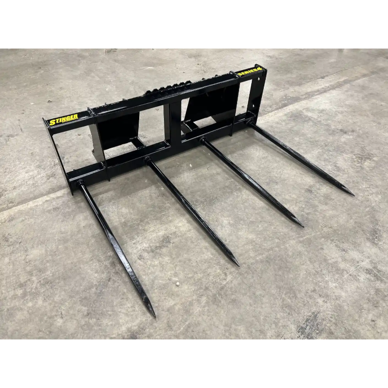 Black steel skid steer bale spear attachment with four long pointed tines on concrete floor viewed from front angle