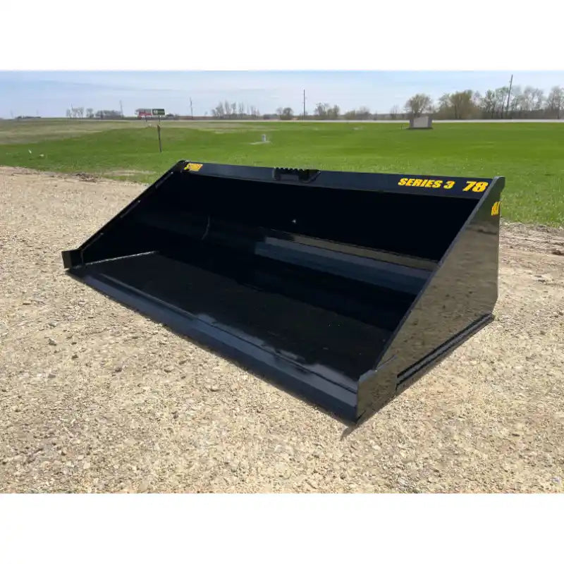 Black steel skid steer bucket with smooth sides and yellow Series 3 78 decal on gravel and grass background