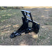Black steel tractor-mounted tree puller attachment with serrated gripping teeth and hydraulic cylinders on grass surface
