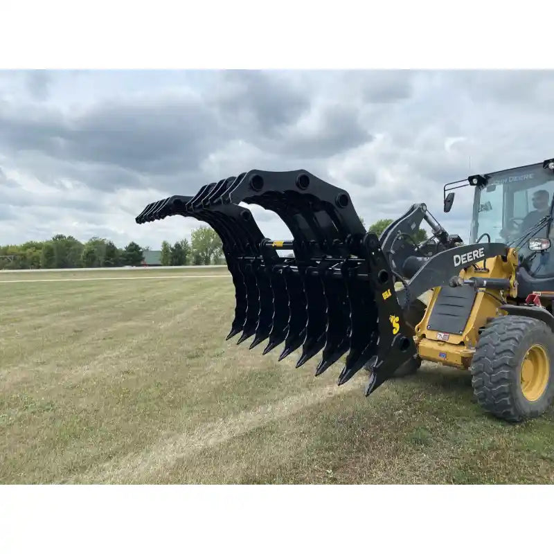 Black steel tractor clam grapple attachment with multiple curved tines mounted on yellow loader arm outdoors