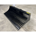 Left angled view of black metal skid steer rock bucket attachment with widely spaced curved tines and reinforced mounting plate on concrete floor