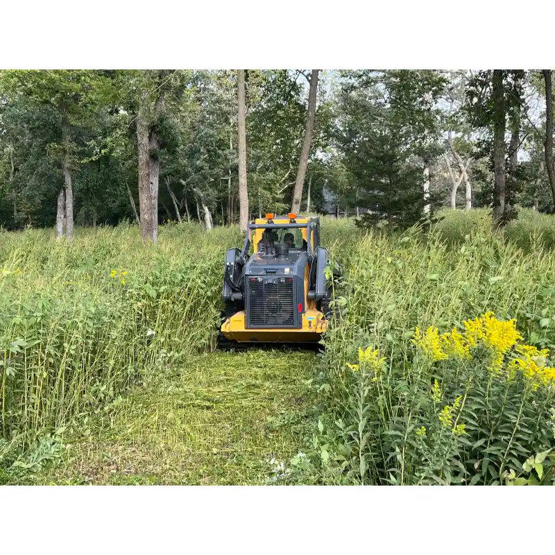 Skid steer brush cutter clearing dense vegetation in a wooded area viewed from front gallery position 15 square image