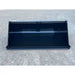 Front view of black steel tractor bucket attachment resting on compacted gravel surface outdoors
