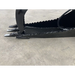 Black skid steer grapple bucket attachment with serrated curved arm, three flat digging teeth, and hydraulic hose on concrete floor