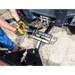 Close-up of hands in gloves attaching Swisher 62-inch plow rolled blade mount to utility vehicle front, soil surface visible gallery 1