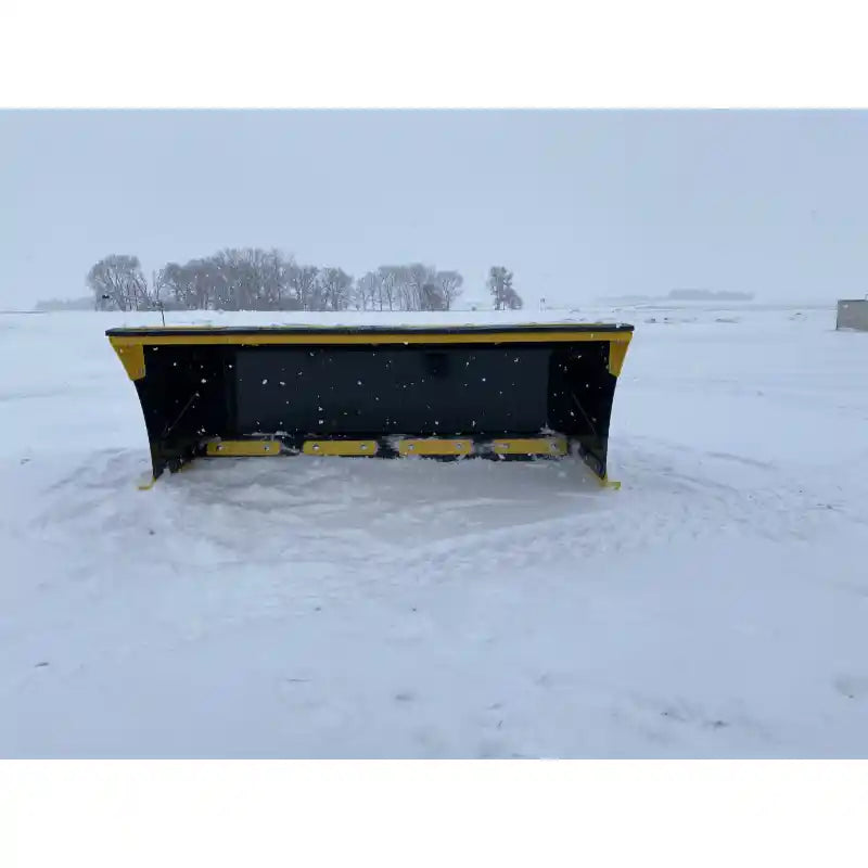 Front view of black and yellow skid steer snow pusher attachment on snow-covered flat terrain outdoors