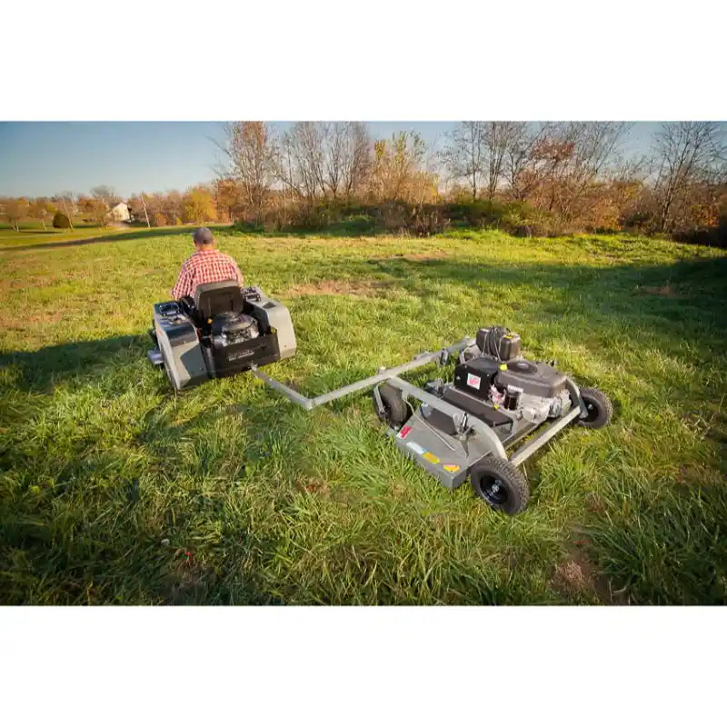 Rear view of operator on zero-turn mower towing Swisher 60-inch finish cut mower with 15.5HP engine, gallery position 1