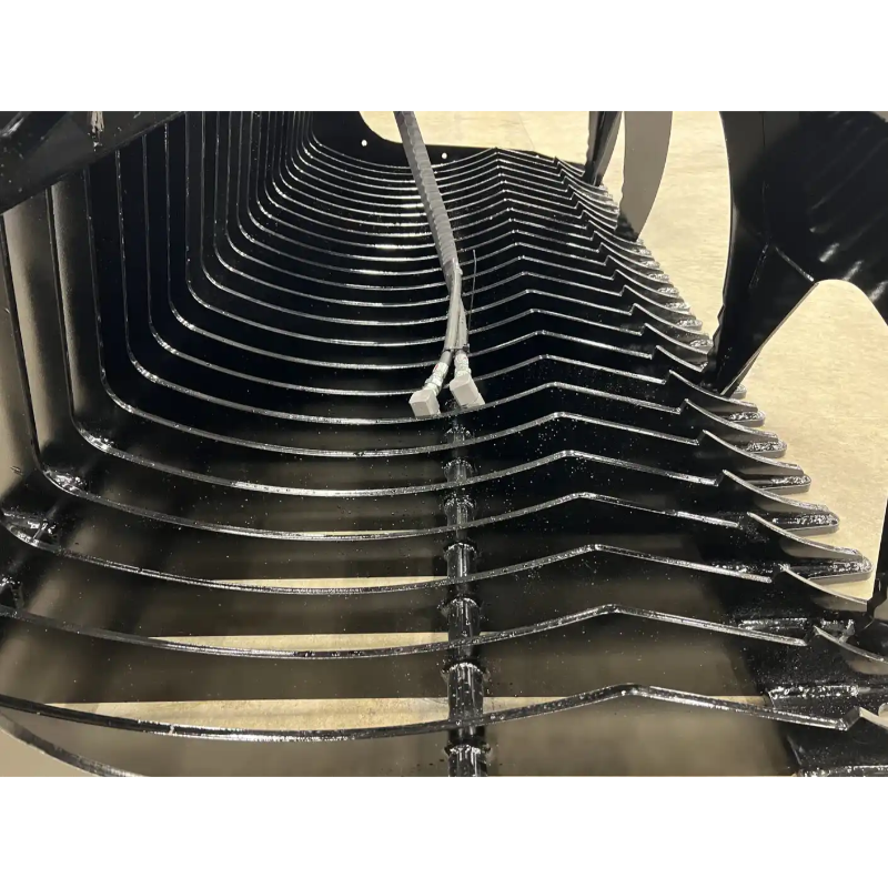 Interior view of black skid steer rock grapple attachment showing curved steel tines and hydraulic hose connections