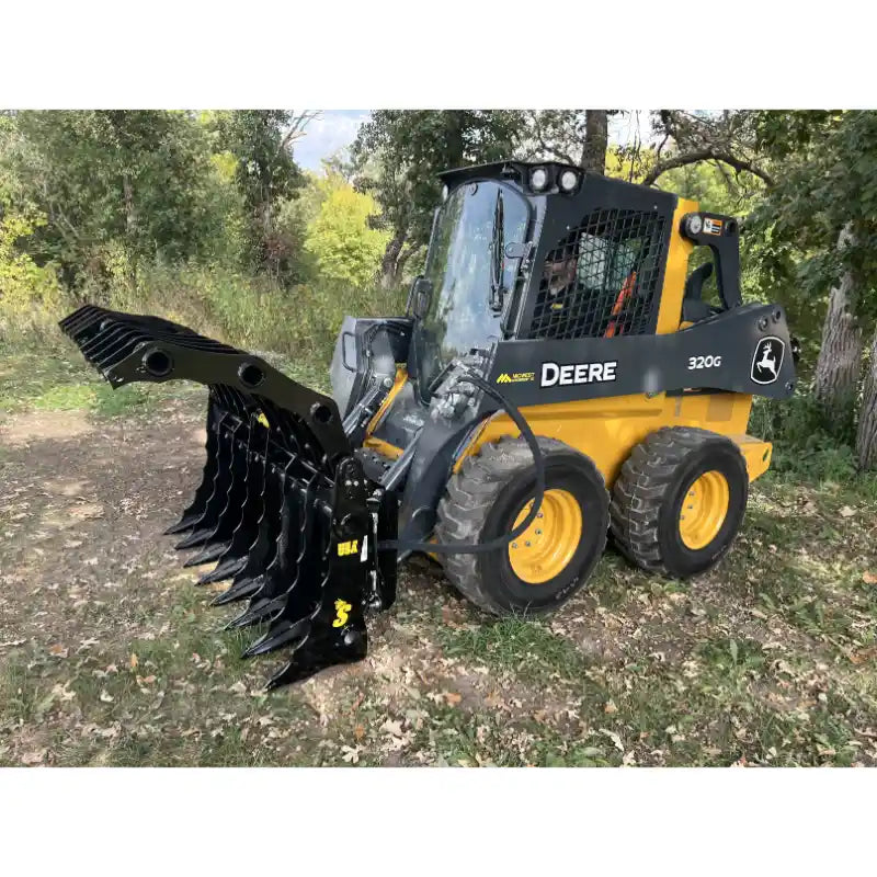 Yellow John Deere skid steer loader with black hydraulic grapple attachment outdoors on grass and dirt near trees