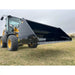 Front view of black steel tractor hydraulic dump bucket attachment raised on yellow loader on grass field