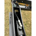 Close-up of black painted hydraulic hose and metal fitting inside rectangular steel frame section on equipment over grass field
