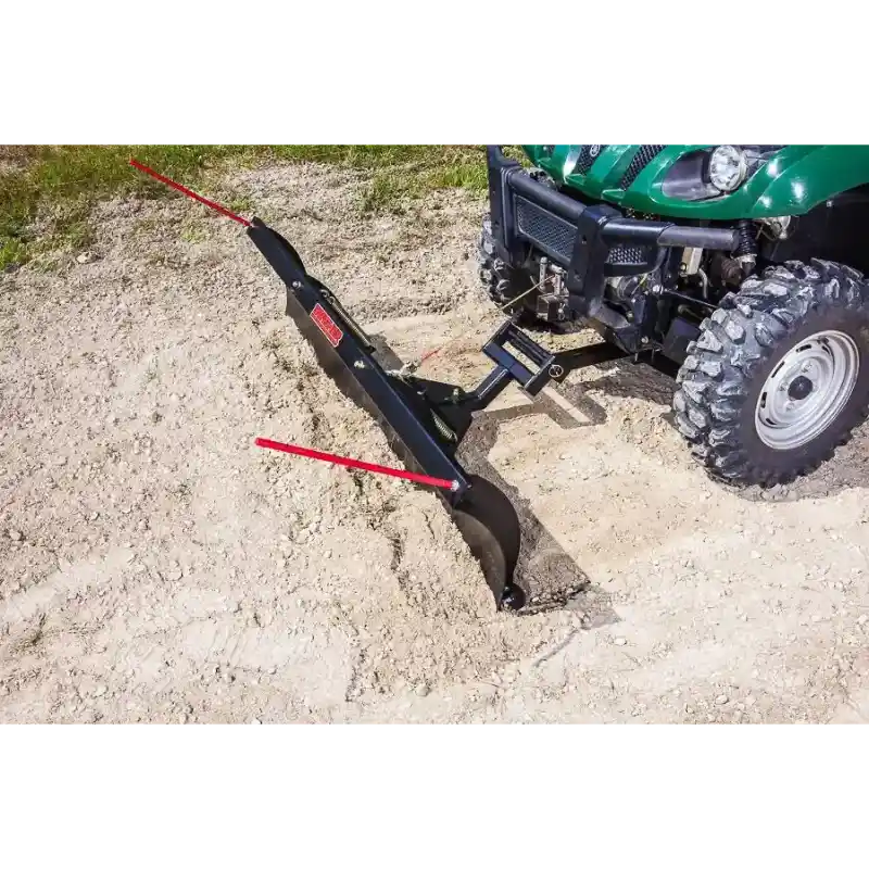 Angle plow attached to green UTV digging into loose soil with red guide markers, gallery position 1