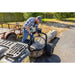 Operator using Swisher ATV log skidder with hand crank winch to lift large log on paved surface, gallery position 1