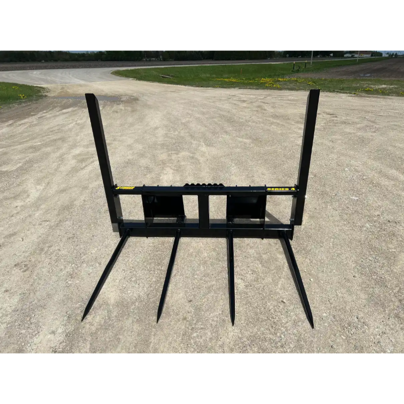 Black metal skid steer attachment with four pointed tines and vertical support arms on dirt surface viewed from front angle