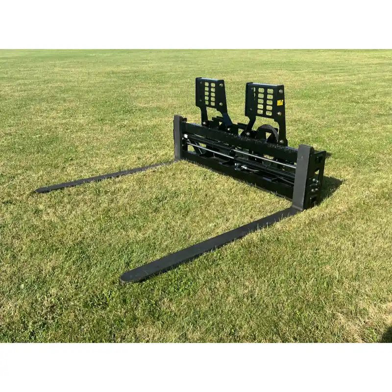 Black steel skid steer pallet fork attachment with reinforced backrest and two long forks resting on grass