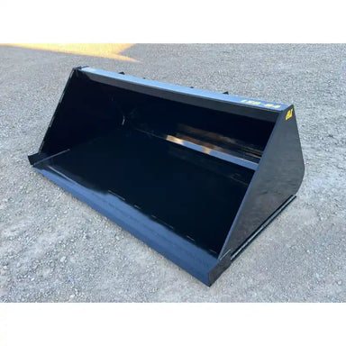 Wide black steel liquid slurry bucket attachment angled to show interior and side on gravel surface outdoors