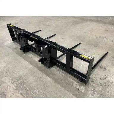 Black steel skid steer attachment with four pointed tines for lifting or moving materials on concrete floor