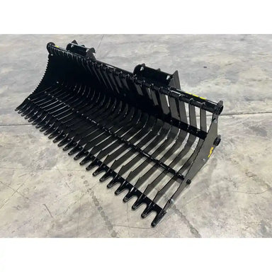 Black metal rock bucket attachment with curved tines and mounting brackets on concrete floor surface