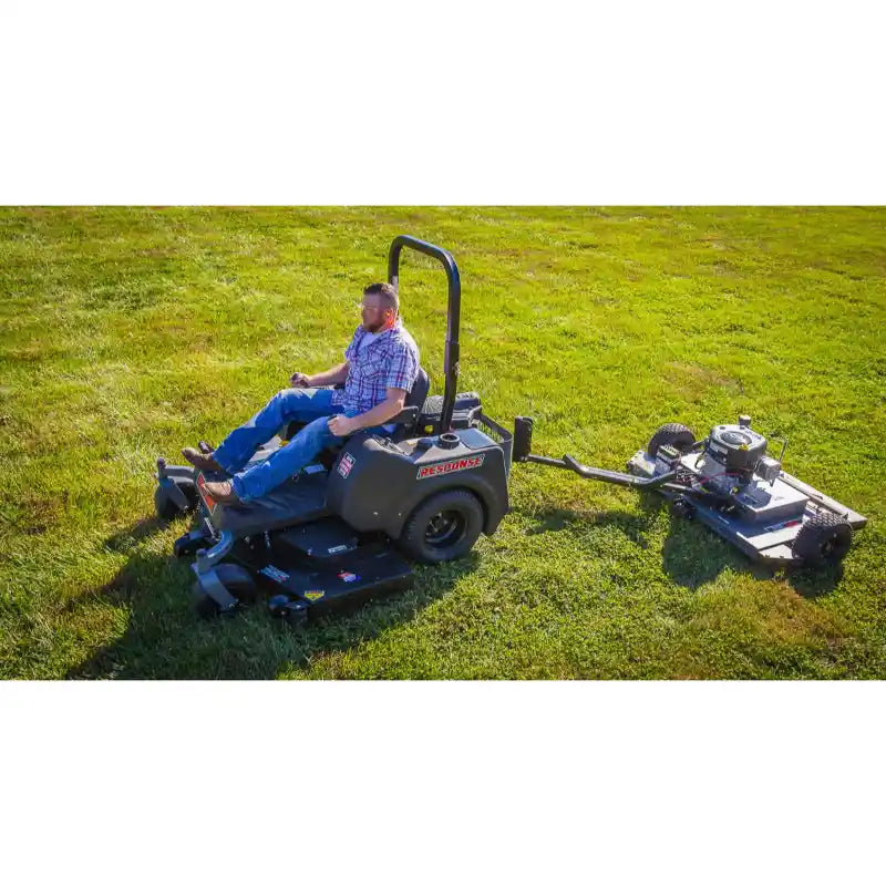 Operator using a ride-on mower towing a Swisher 44-inch finish cut mower on a grassy field, gallery position 1