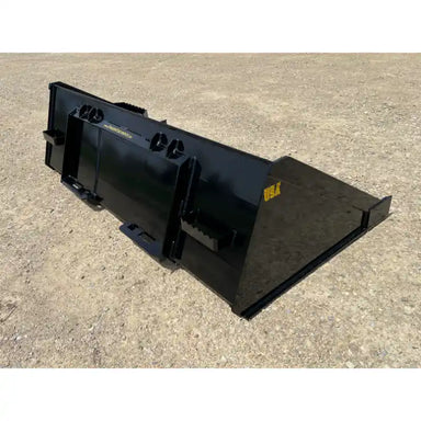 Rear and right side view of a black skid steer material bucket with smooth sides and mounting brackets on dirt surface