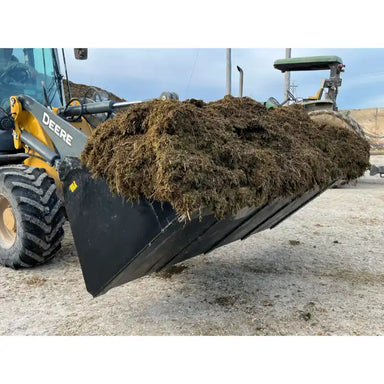 Front-left view of black skid steer high-volume bucket attachment carrying loose organic material outdoors