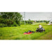 Rear view of ATV towing red Swisher 44" rough cut brush mower across tall grass, gallery position 1