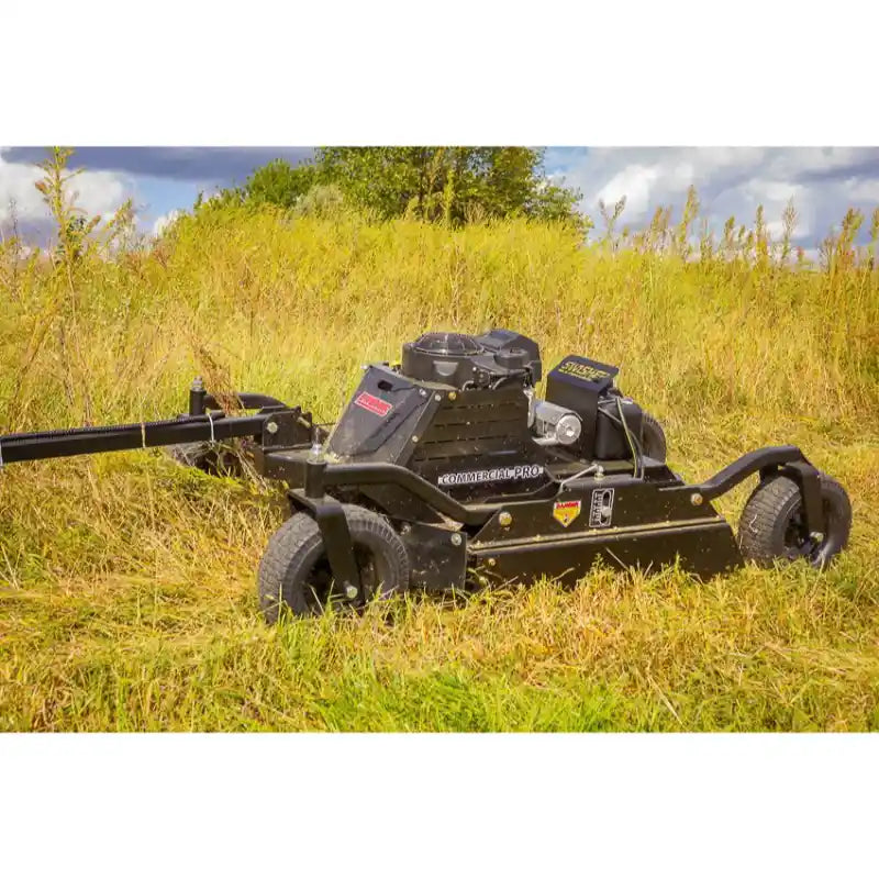 Tow-behind black Swisher 44" brush cutter with 14.5HP Kawasaki engine cutting tall grass, gallery position 1