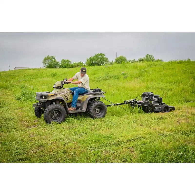 Operator on ATV towing Swisher 44" rough cut mower with 14.5HP engine across grassy field, gallery position 1